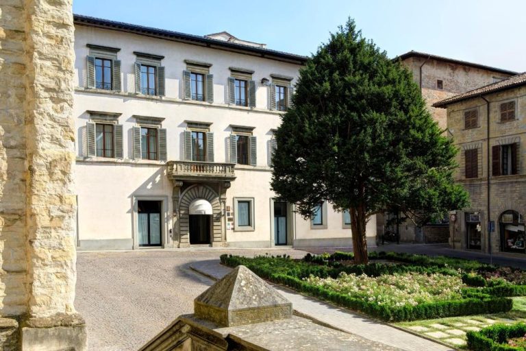 Fachada exterior del Hotel Tiferno con jardín y árbol en plaza histórica italiana