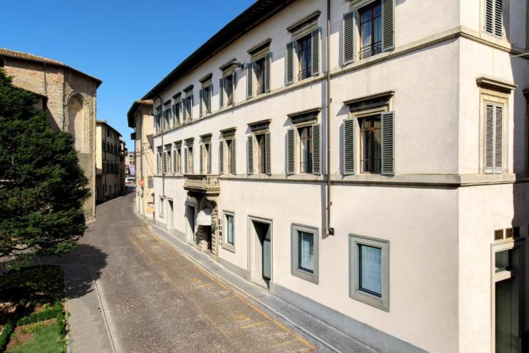 Fachada exterior del Hotel Tiferno, edificio histórico con persianas verdes en calle empedrada italiana
