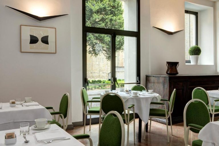 Restaurante interior del Hotel Tiferno con mesas blancas y sillas verdes con vistas al jardín
