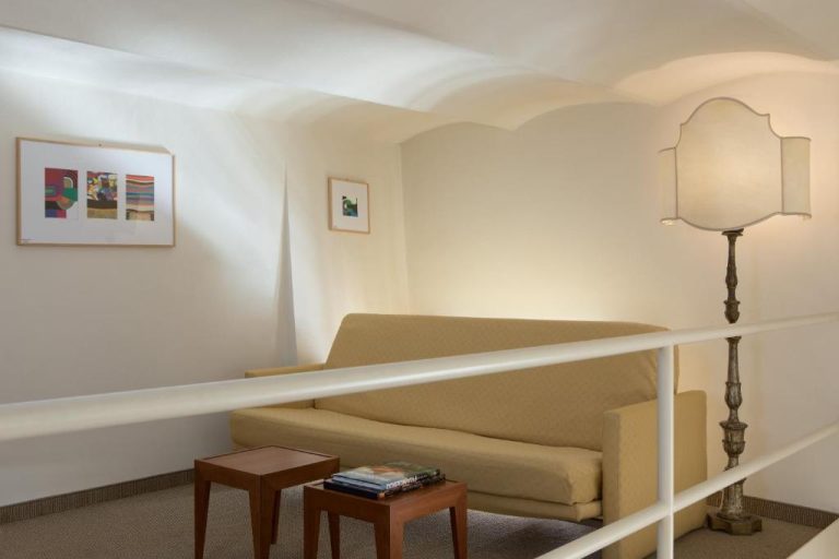 Salón interior con sofá beige y lámpara de pie elegante en el Hotel Tiferno