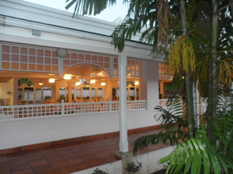 Terraza exterior con restaurante iluminado y palmeras tropicales del Hotel PomMarine