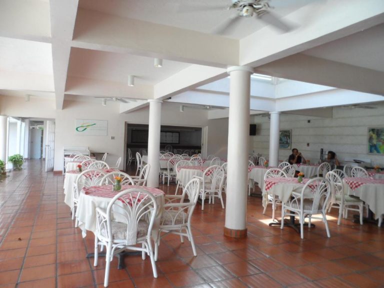 Restaurante interior del Hotel PomMarine con mesas de mantel a cuadros rojos y sillas blancas de mimbre