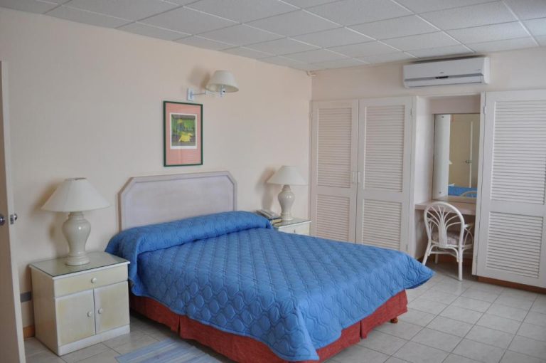 Habitación doble con cama matrimonial y colcha azul en Hotel PomMarine con aire acondicionado