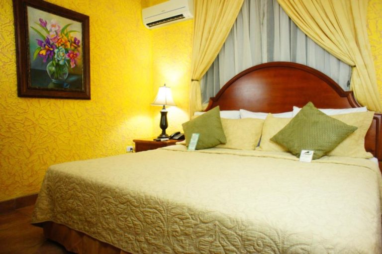 Habitación doble con cama matrimonial y decoración clásica en amarillo del Hotel Cafe
