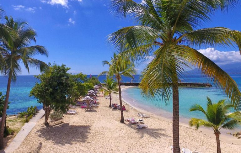 Playa privada con palmeras y tumbonas del Mahogany Hotel Residence & Spa en aguas turquesas del Caribe