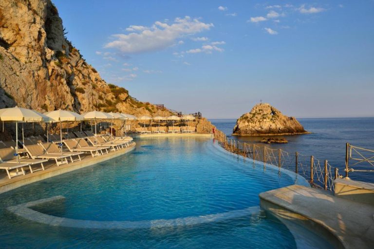 Piscina infinita con vistas al mar y tumbonas del UNA Hotels Capotaormina en Sicilia