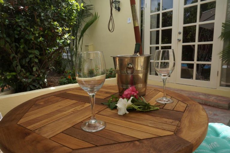 Terraza exterior del Wonders Boutique Hotel con mesa de madera, copas de vino y cubo de hielo entre flores