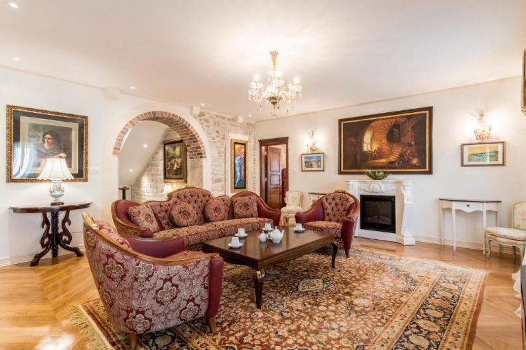 Elegante salón clásico con sofás tapizados, chimenea y pinturas en Villa Nepos Hotel