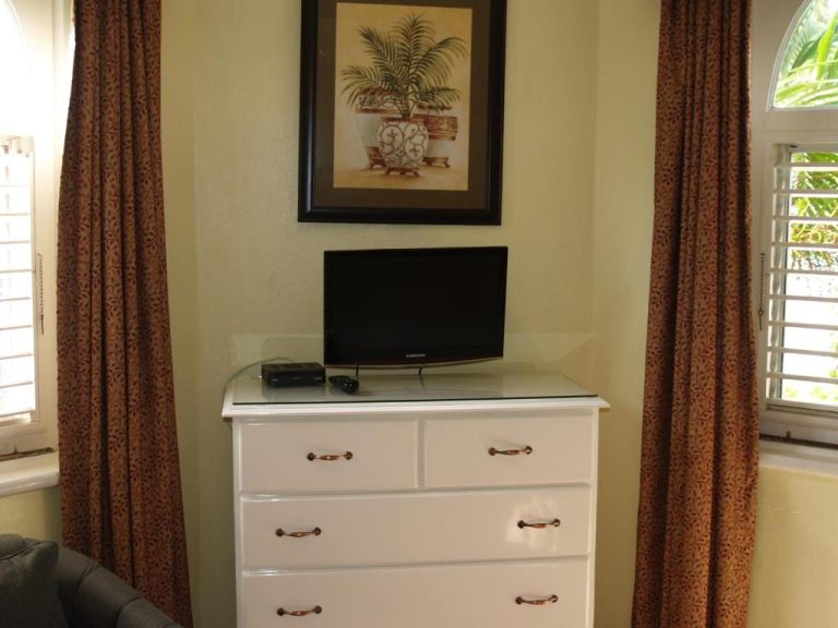 Habitación con televisor Samsung y cómoda blanca en Sandcastles Resort Ocho Rios, Jamaica