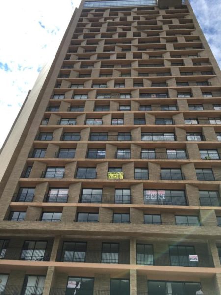 Fachada exterior del edificio de apartamentos Enjoy In Bogotá con balcones y letreros de arriendo