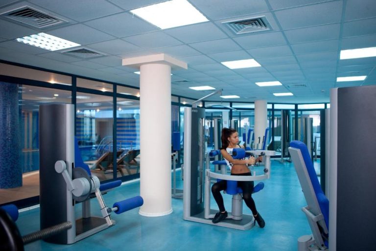 Gimnasio moderno con máquinas de musculación azules en el Astera Hotel & Spa con acceso a playa privada