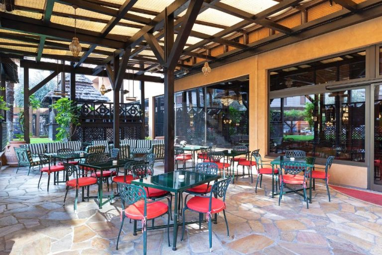 Terraza exterior del Royal Hotel Carlton con mesas y sillas de hierro forjado con cojines rojos