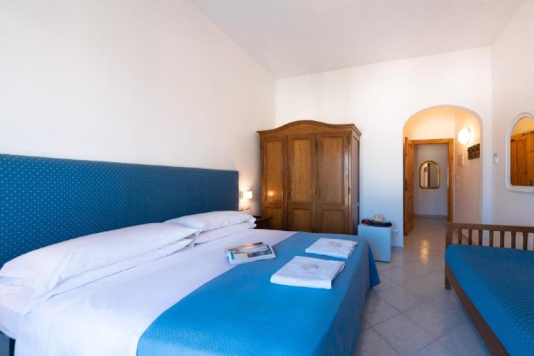 Habitación doble con cabecero azul y armario de madera en Hotel Europa
