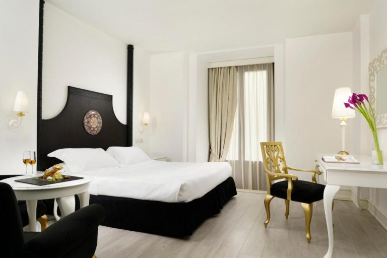 Habitación doble de lujo con cama de dosel negra y decoración elegante en Palace Catania UNA Esperienze