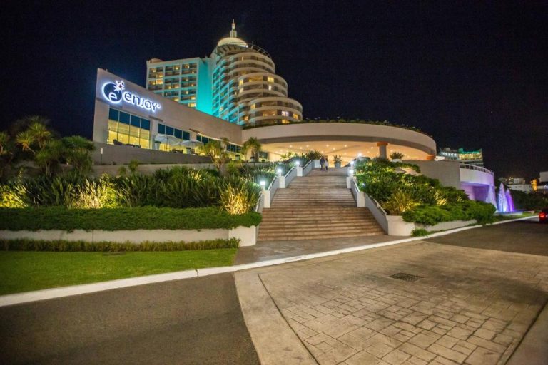Fachada exterior iluminada del casino y hotel Enjoy Punta del Este vista nocturna con jardines