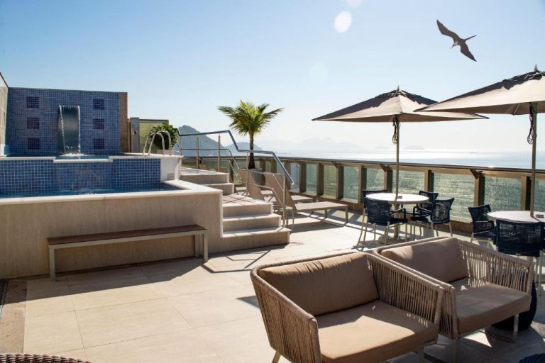Terraza con piscina, tumbonas y vistas al mar del Hotel Astoria Palace en Río de Janeiro
