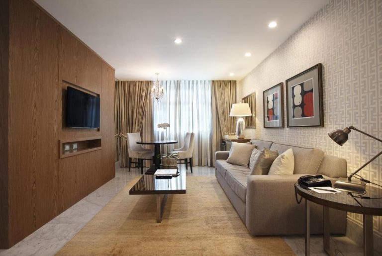 Salón elegante de suite con sofá, TV empotrada y decoración moderna en Miramar By Windsor Copacabana