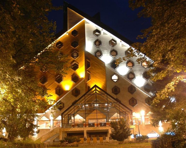 Fachada exterior nocturna del Bianca Resort & Spa con arquitectura moderna y ventanas hexagonales iluminadas