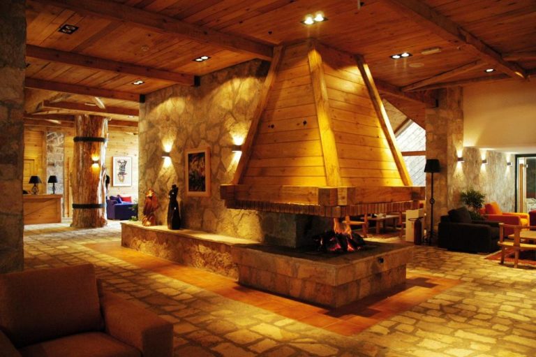 Lobby con chimenea central de piedra y madera en el Bianca Resort & Spa, ambiente rústico y acogedor