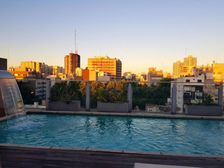 Piscina rooftop con cascada y vistas panorámicas de Buenos Aires al atardecer en Fierro Hotel