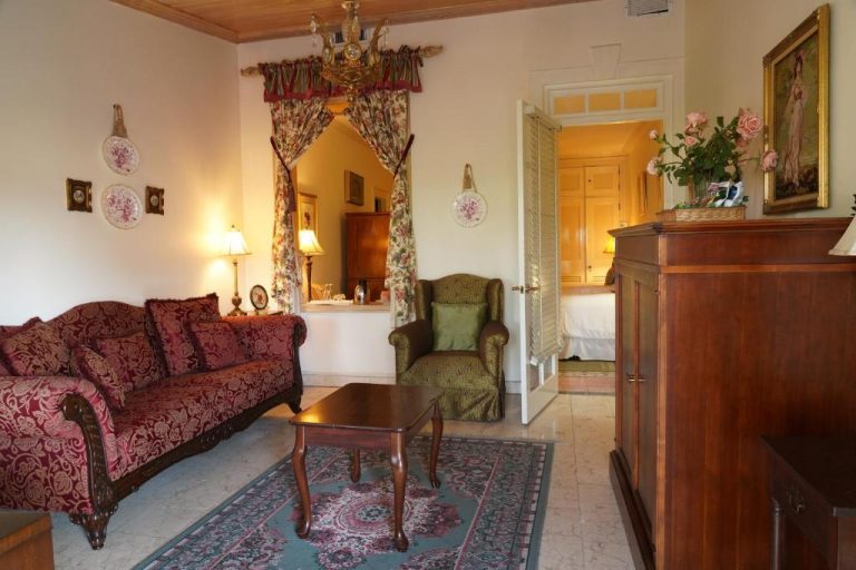Elegante salón clásico con sofá rojo y muebles de madera en la suite del Graycliff Hotel