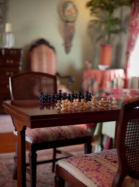 Elegante sala de ajedrez con mesa de madera y piezas artesanales en el histórico Graycliff Hotel