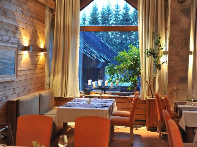 Restaurante interior del Bianca Resort & Spa con mesas elegantes, iluminación cálida y vistas al bosque