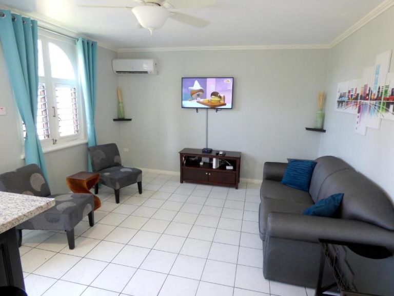 Sala de estar con sofá, televisión y aire acondicionado en Beach One Bedroom Suite A17