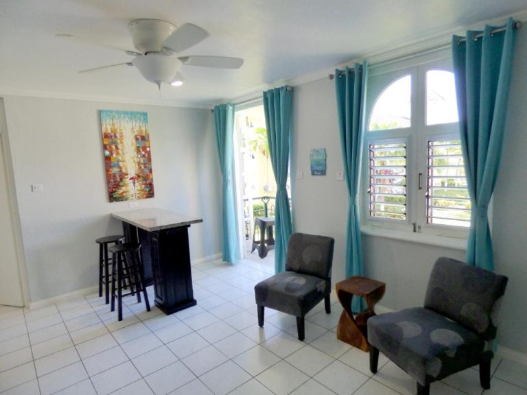 Sala de estar con sillas, barra de bar y cortinas turquesas en Beach One Bedroom Suite A17