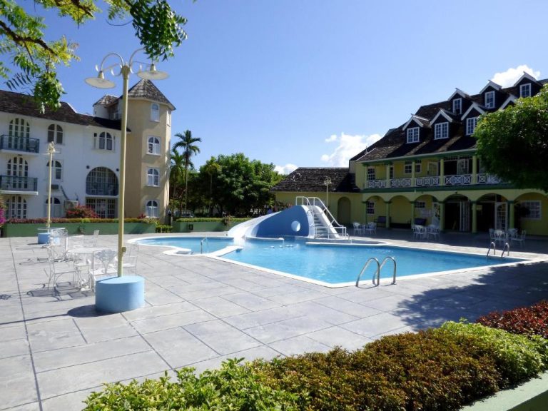 Piscina exterior con tobogán y zona de descanso del Beach One Bedroom Suite A17 en Jamaica