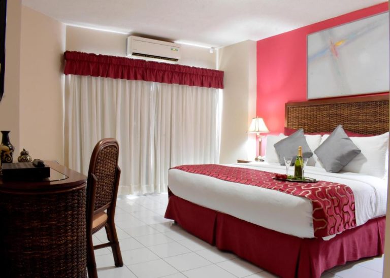 Habitación doble con cama king size y decoración en rojo del Aparthotel Guijarros