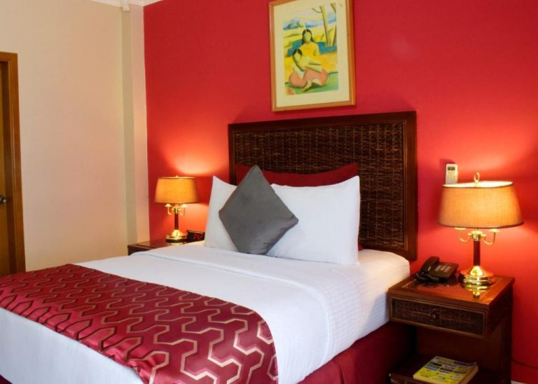 Habitación doble con cama king size y decoración en rojo del Aparthotel Guijarros