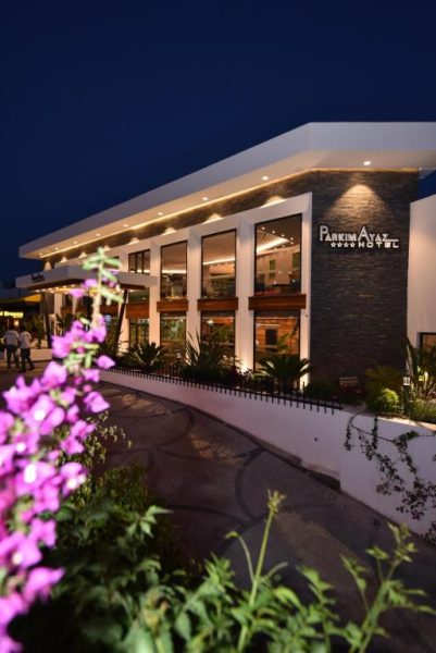 Fachada exterior iluminada del Parkim Ayaz Hotel de noche con jardín y flores