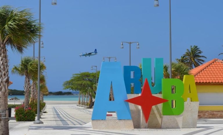 Letras gigantes de Aruba con estrella roja frente a la playa en voco Surfside Aruba by IHG