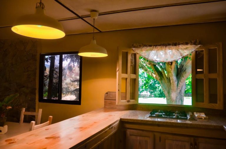 Cocina rústica con encimera de madera y ventana con vistas al jardín en Hotel Rancho Constanza