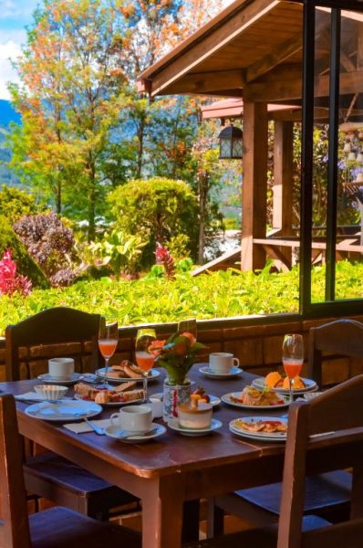 Desayuno servido en terraza con vista al jardín tropical en Hotel Rancho Constanza & Cabañas de la Montaña