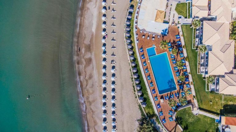 Vista aérea de la piscina exterior y playa privada con hamacas del Crystal Beach Hotel