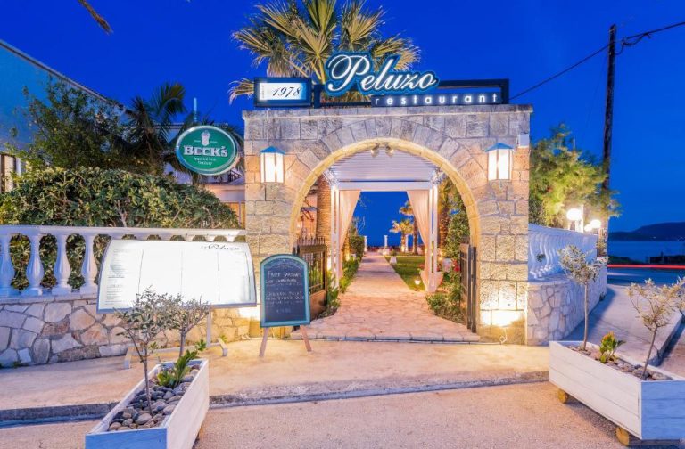 Entrada iluminada del restaurante Peluzo en Crystal Beach Hotel con arco de piedra y ambiente nocturno