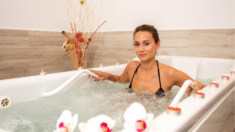 Mujer relajándose en jacuzzi con velas y orquídeas en el spa del Astera Hotel & Spa