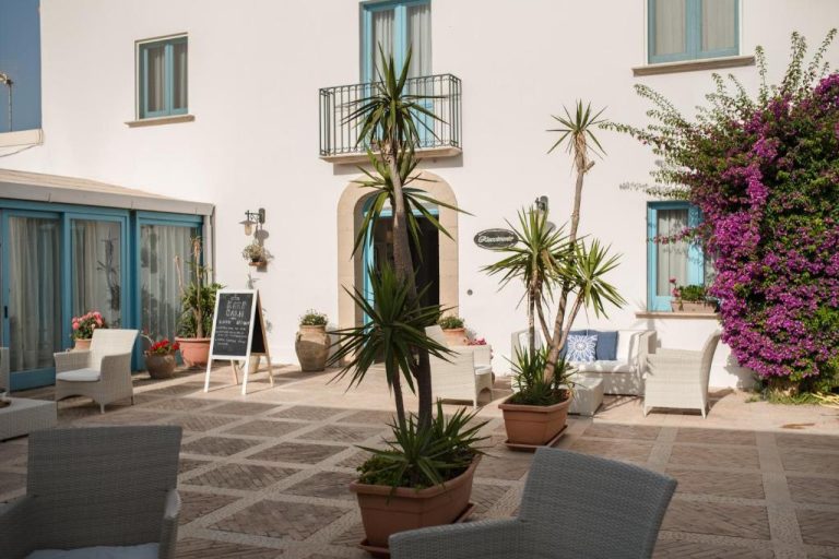 Terraza exterior con palmeras y zona de descanso del Relais Antiche Saline en Puglia