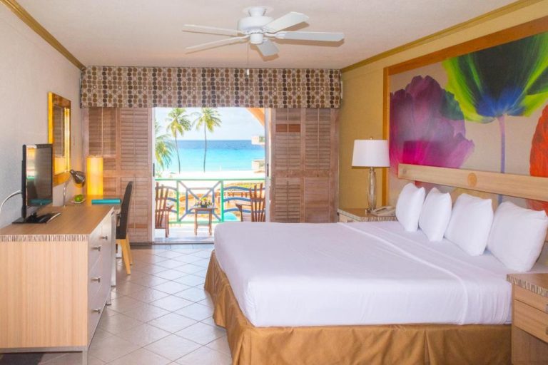 Habitación con cama king y balcón con vistas al mar turquesa en Accra Beach Hotel & Spa Barbados