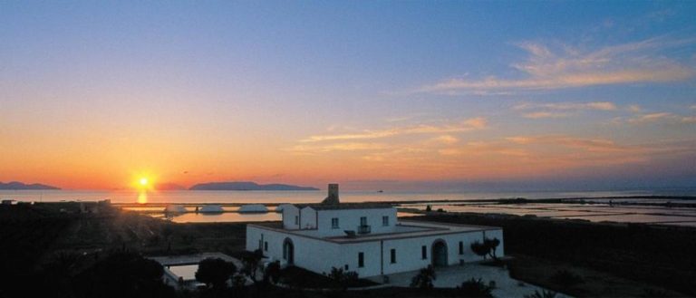 Vista panorámica del Relais Antiche Saline al atardecer con salinas y vistas al mar de Sicilia