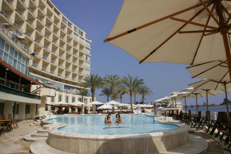 Piscina exterior con sombrillas y palmeras del Hotel Palestine Montaza en Alejandría, Egipto
