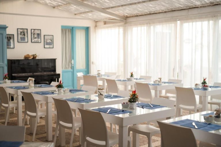 Comedor del Relais Antiche Saline con mesas blancas y manteles azules listos para el desayuno