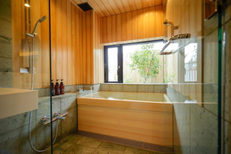 Baño japonés con bañera de madera hinoki y ducha en el Kaminarimon Ryokan