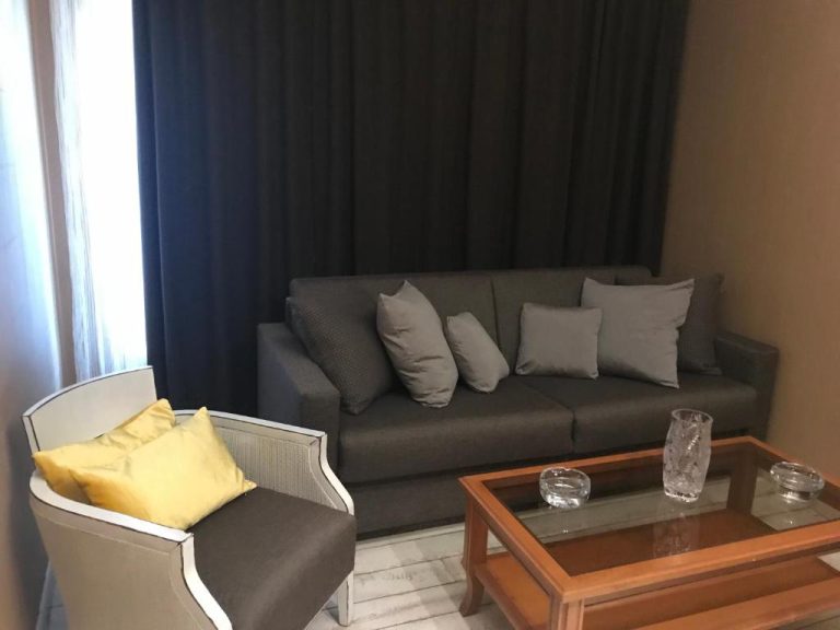 Salón moderno con sofá gris, sillón y mesa de centro de cristal en Hotel Levadia