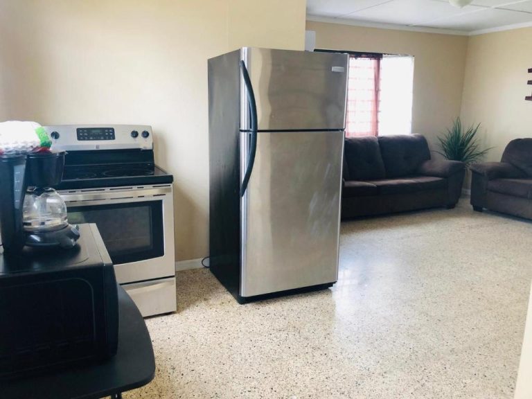 Cocina equipada con nevera, cocina eléctrica y cafetera en el Arecibo Inn con salón integrado