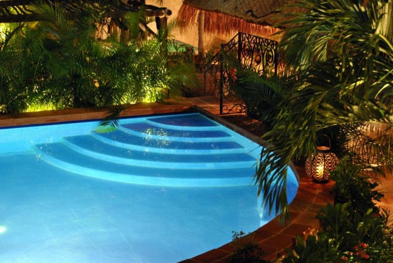 Piscina iluminada de noche con escalinatas y jardín tropical en La Pasion Colonial Hotel Boutique By Bunik