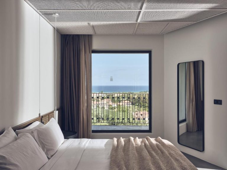 Habitación elegante con cama doble y ventanal con vistas al mar en Zante Maris Suites Adults Only