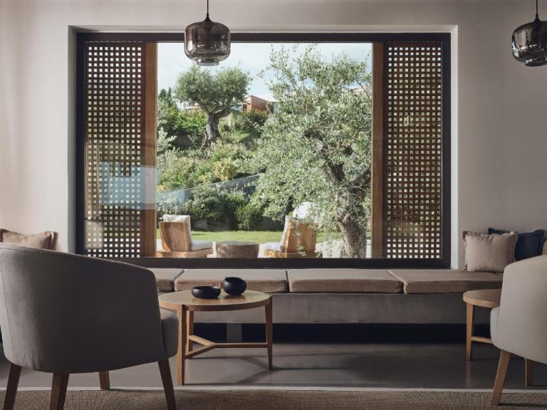 Salón elegante con ventanal panorámico y vistas al jardín con olivos en Zante Maris Suites Adults Only